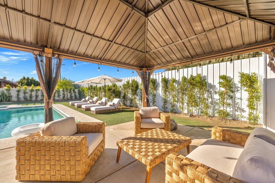 Shaded outdoor lounge w/ woven seating overlooking the pool for breezy hangouts.