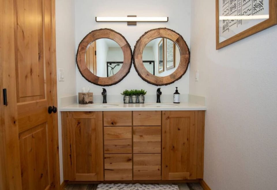 Bathroom vanity w/ double mirrors, warm wood cabinetry, and clean modern style.