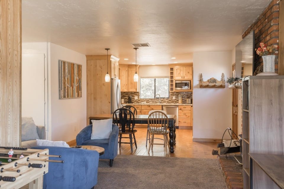 Living area w/ blue accent chairs, dining table & kitchen beyond.