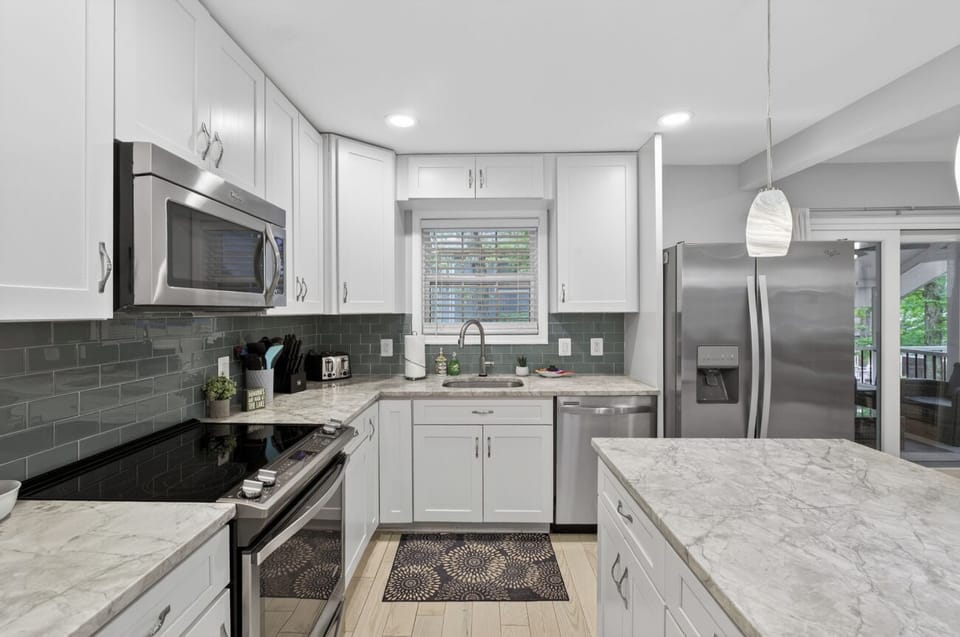 Sleek chef’s kitchen w/ island, stainless appliances & porch view