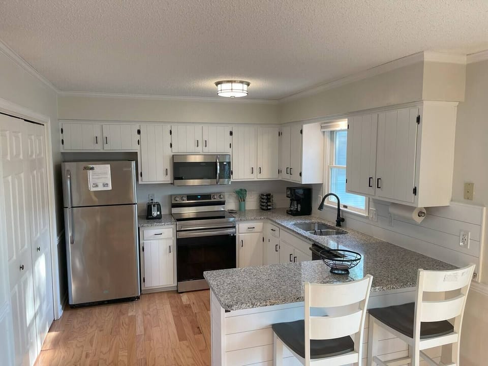 Coastal dreams do come true with this stunning kitchen. The combination of sleek granite countertops and a shiplap backsplash creates the perfect balance of modern and rustic charm.  #CoastalKitchenGoals #GraniteCountertops #ShiplapLove #SeasideL