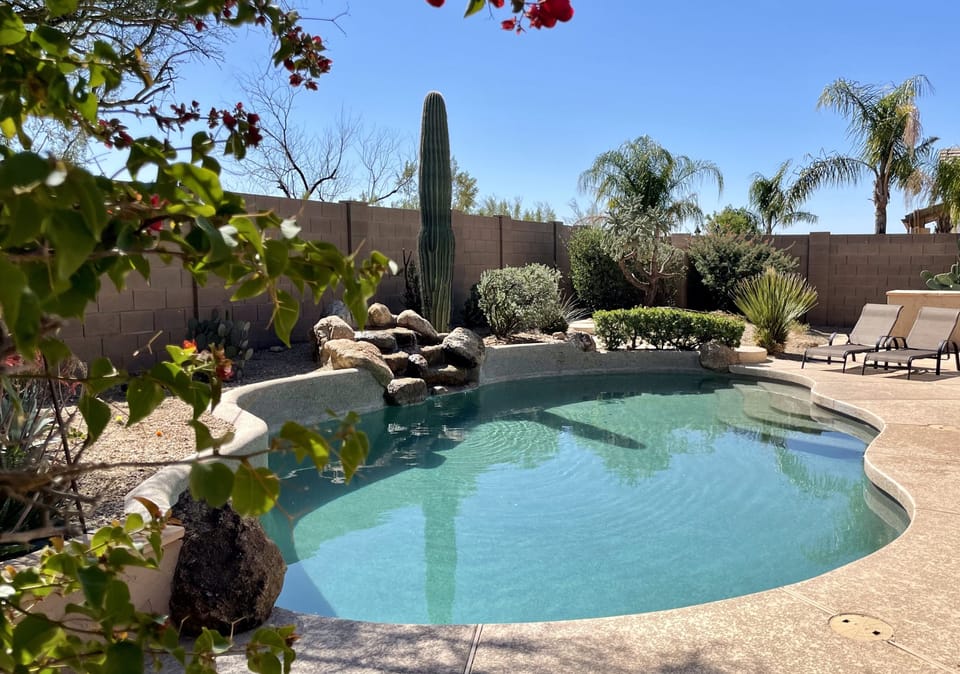 Backyard heated pool with waterfall. Built-in grill.
