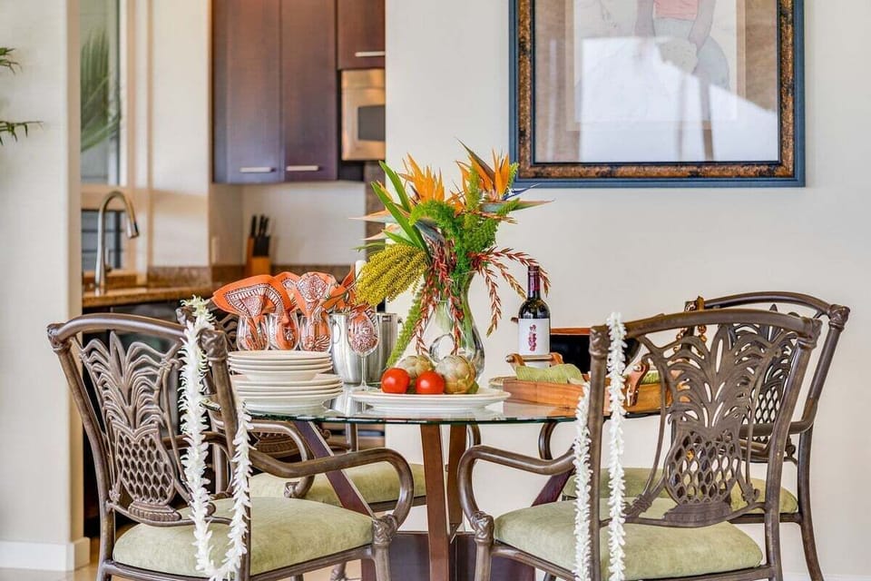 Covered lanai dining area with table seating and lush tropical views, perfect for alfresco meals in Maui's warm island climate.