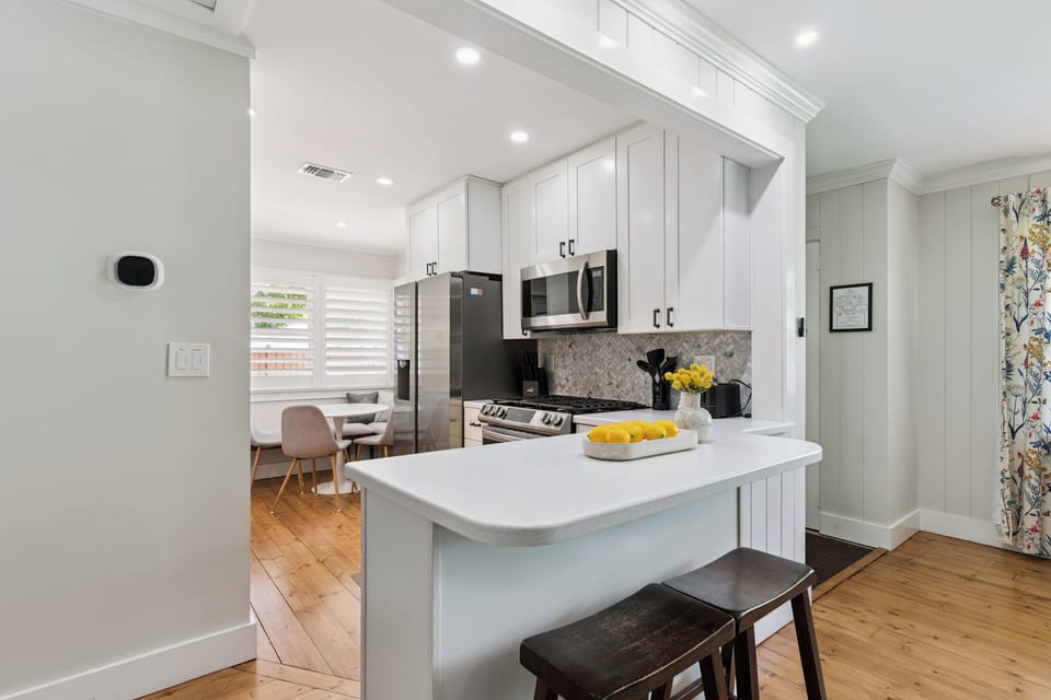 Your bright, modern kitchen awaits with sleek white cabinetry, stainless steel appliances, and a breakfast island perfect for morning coffee or meal prep.