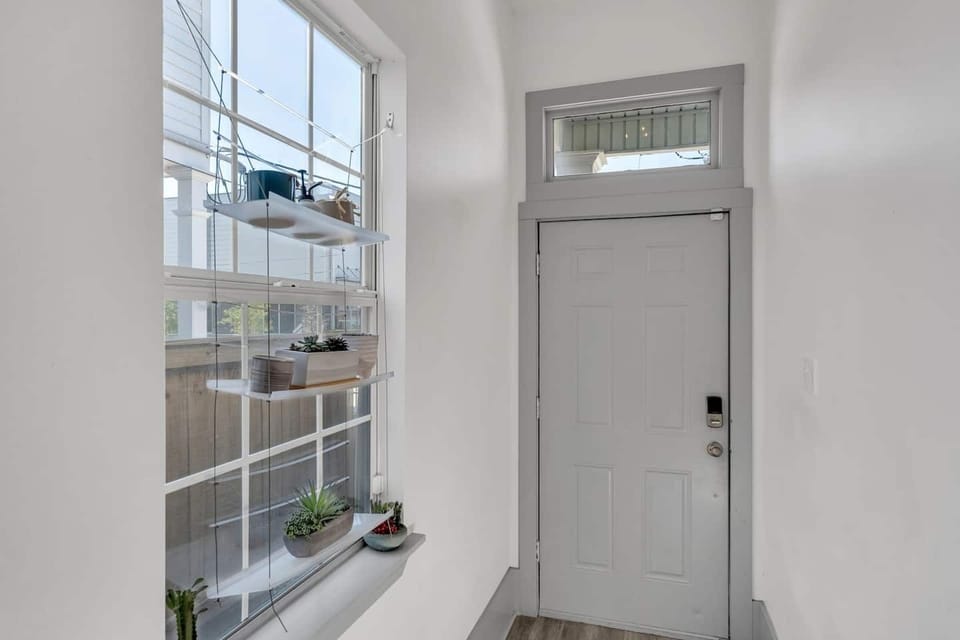The soft gray tones and natural light create a warm, inviting atmosphere, while the hanging shelves with greenery add a refreshing touch of nature.