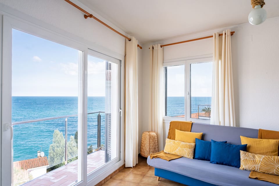 Living room on the first floor with unobstructed sea views and balcony access — the kind of view that makes a family holiday feel effortless from the moment you wake up.