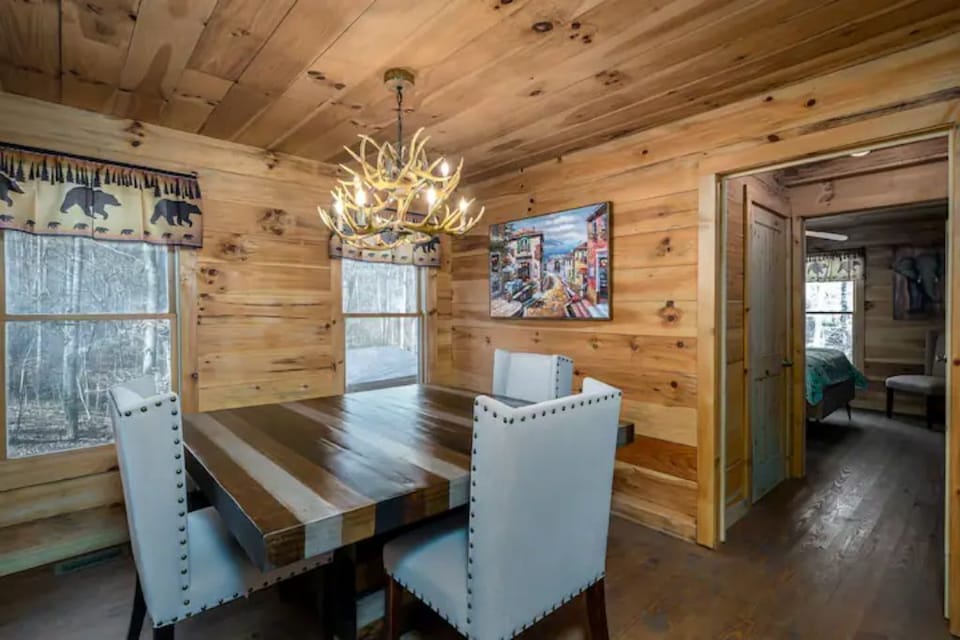 View of dining area & hall to bathroom & main floor bed room. 6 chairs & bench.