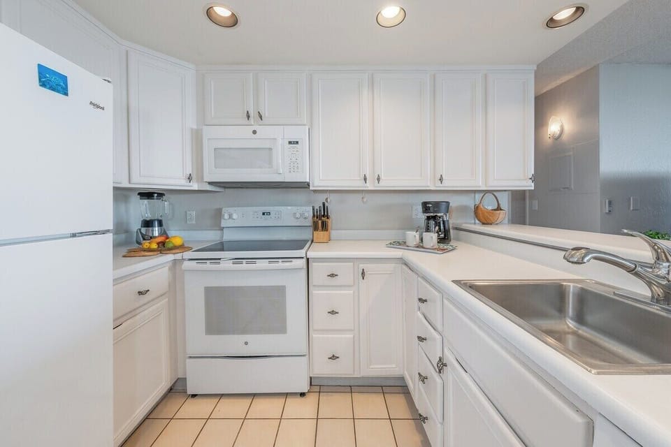 Bright, fully equipped kitchen with white appliances and ample space
