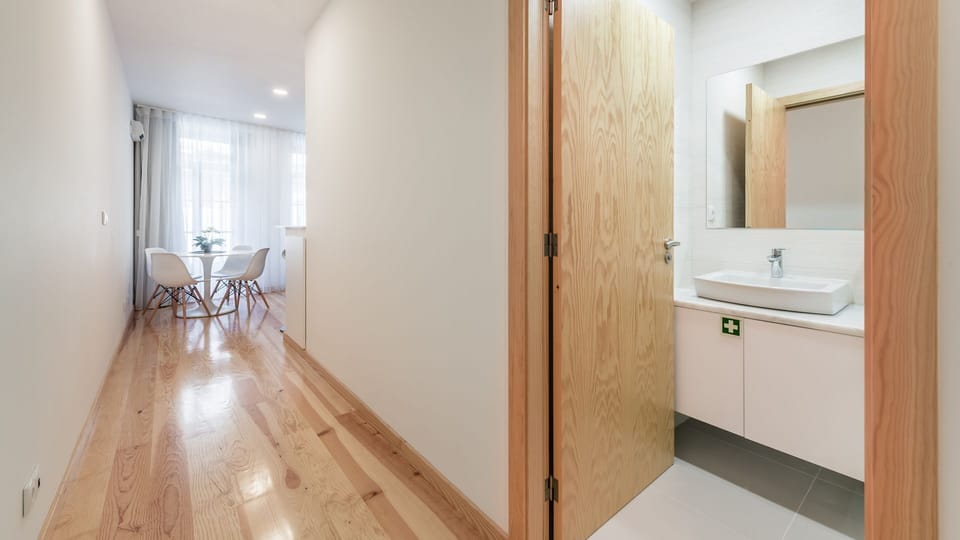 Walk through a sleek hallway where bright natural light from the dining area illuminates your path, with a glimpse into a modern, well-appointed bathroom. The seamless flow provides easy access to all your living spaces.