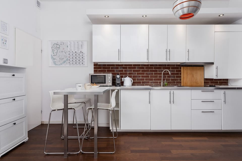 Minimalist white kitchen with a bar counter and stools.
