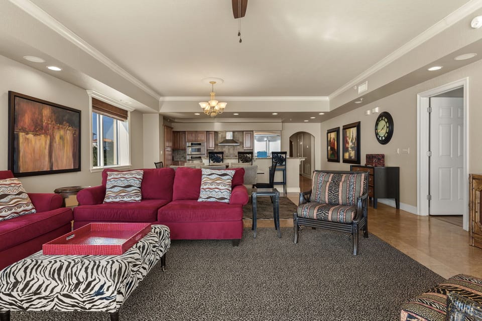 Settle into your stylish open-concept living space with plush burgundy sectional and vibrant patterns, flowing seamlessly into the gourmet kitchen.