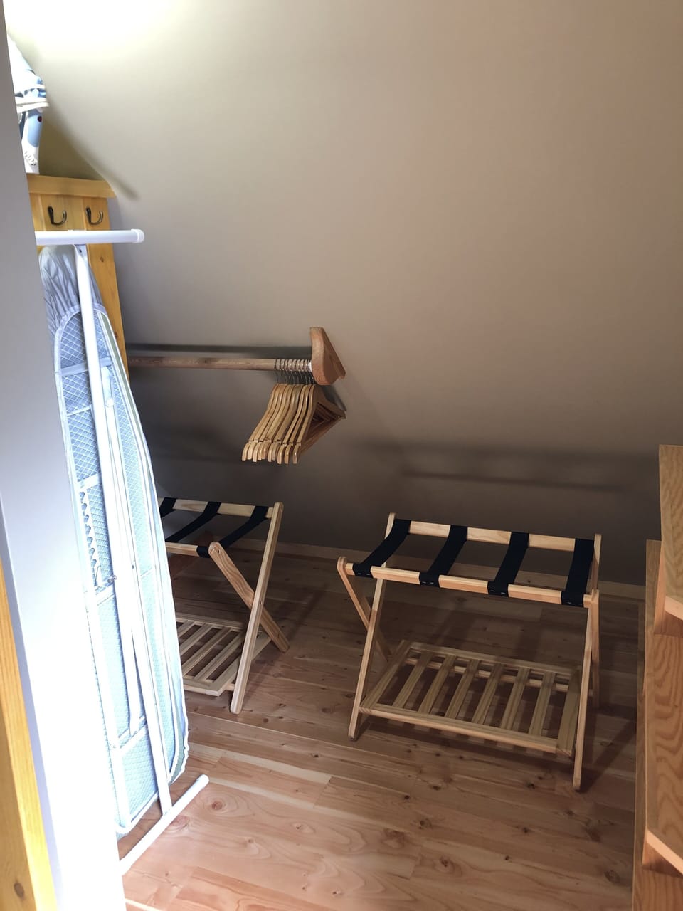 Closet with clothing shelves, luggage racks, clothes hanging, iron with board