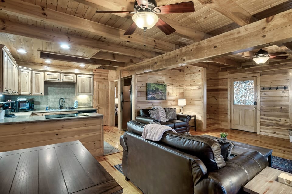 - Open cabin living room with warm wood interiors next to the kitchen   - Comfortable leather seating ideal for relaxing after mountain adventures   - Bright cozy retreat perfect for Smoky Mountain stays and gatherings