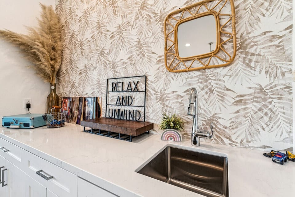 Stylish wet bar area w/ sink, patterned backsplash & decorative accents
