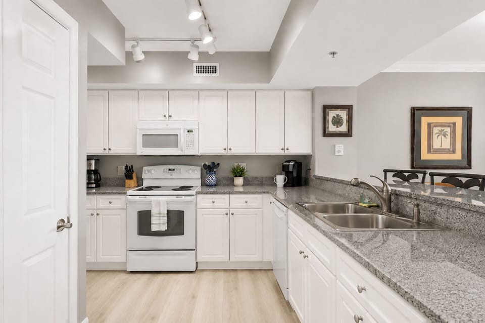 Fully-stocked kitchen, with pots, pans, blender, coffee maker, dishes, cups, mugs, and silverware