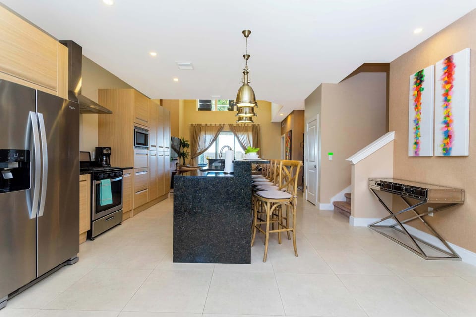 Open-concept kitchen with black-granite island, stainless appliances, pendant lights, and ample bar seating-bright modern hub that flows to the living room.