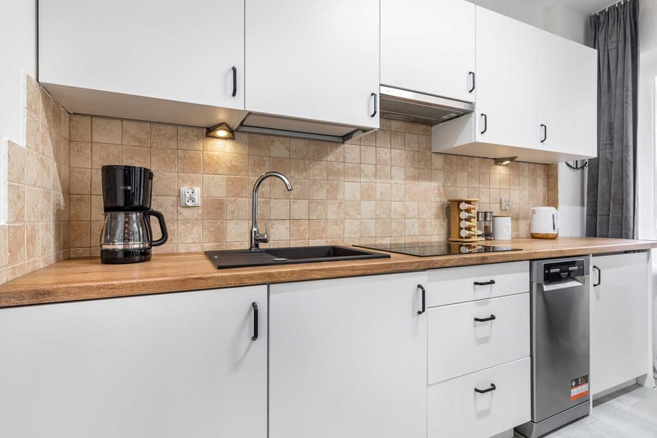 A well-equipped kitchen with white cabinets, wooden countertops, and modern appliances.
