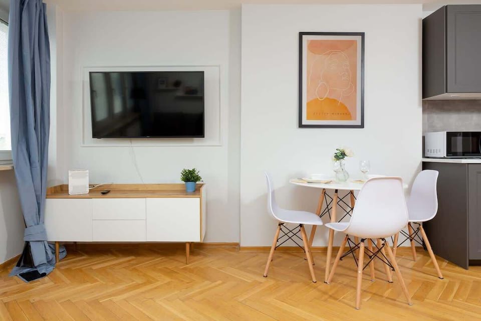 A cozy living area with a wall-mounted TV, a round table, and a stylish sideboard.
