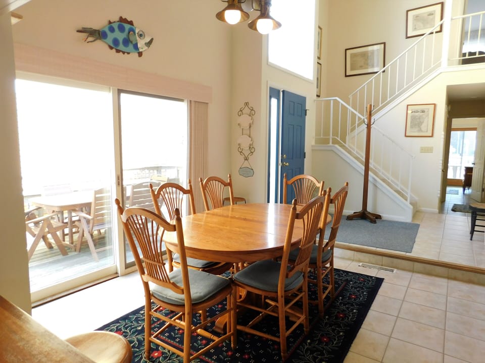 105 Cedarwood Street Dining Room with Sliding Glass Door access - A bright dining space featuring a wooden table and chairs set on a dark rug, with a sliding glass door providing natural light and outdoor access.