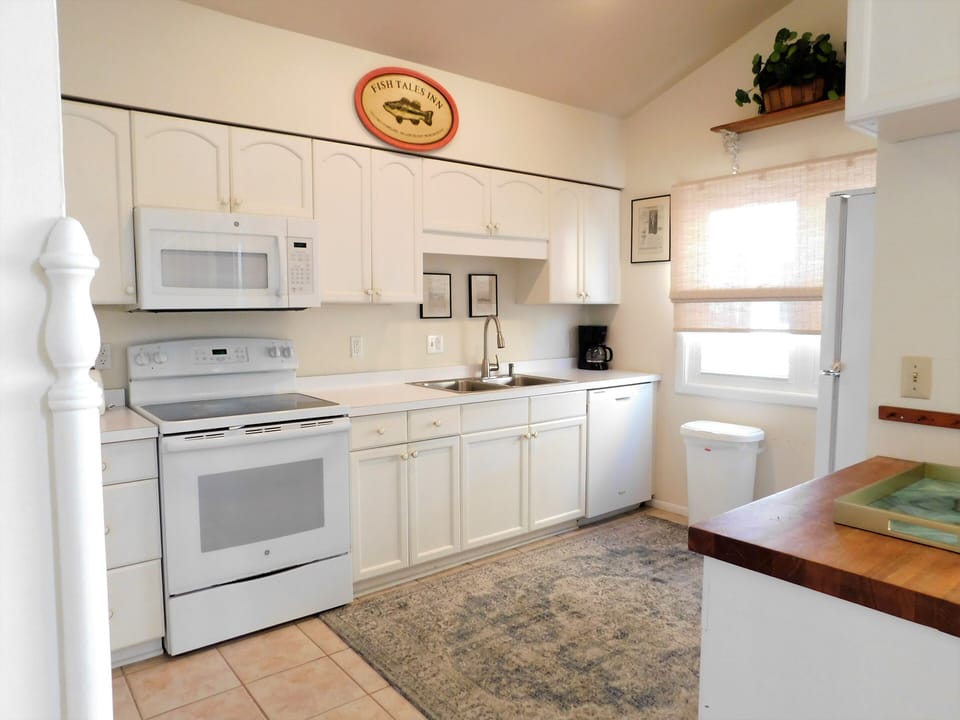105 Cedarwood Street Functional White Kitchen with Ample Cabinet - A bright kitchen space featuring all-white appliances and cabinetry, complemented by light-colored flooring and a window for natural light.