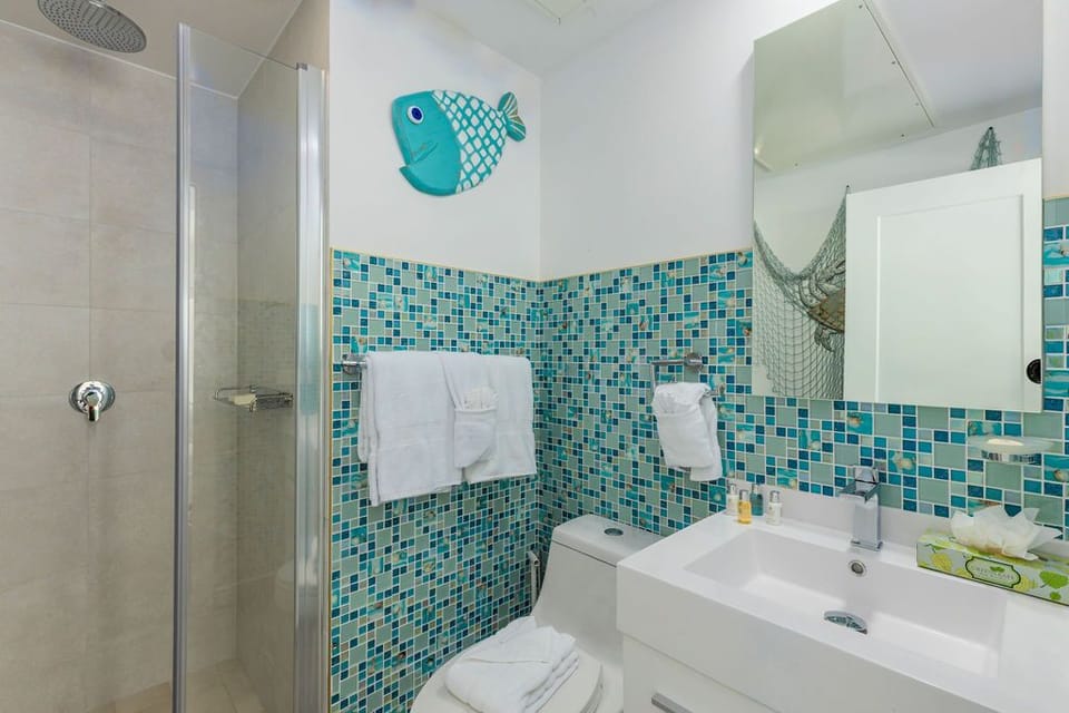 Freshen up in your cheerful bathroom featuring ocean-inspired mosaic tiles, a rainfall shower, and crisp towels ready for your arrival.