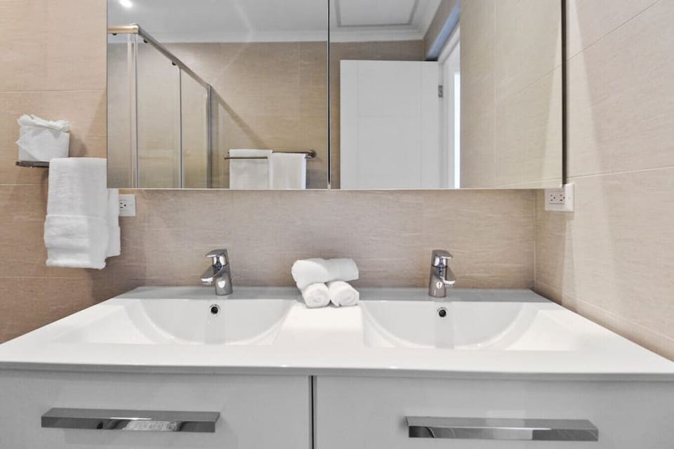 A crisp double-sink vanity offering sleek chrome faucets, large mirrored medicine cabinets, and ample drawer storage for essentials.