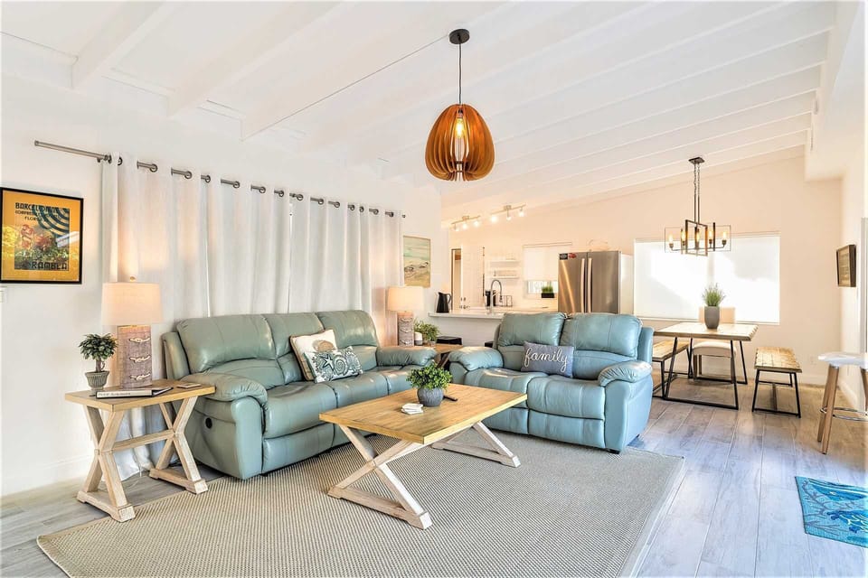 Kitchen is at far end of open great room and has dining table.