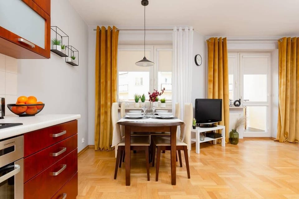 A sleek kitchen with red cabinets, white countertops, and modern appliances. The dining area is adjacent to the cooking space.