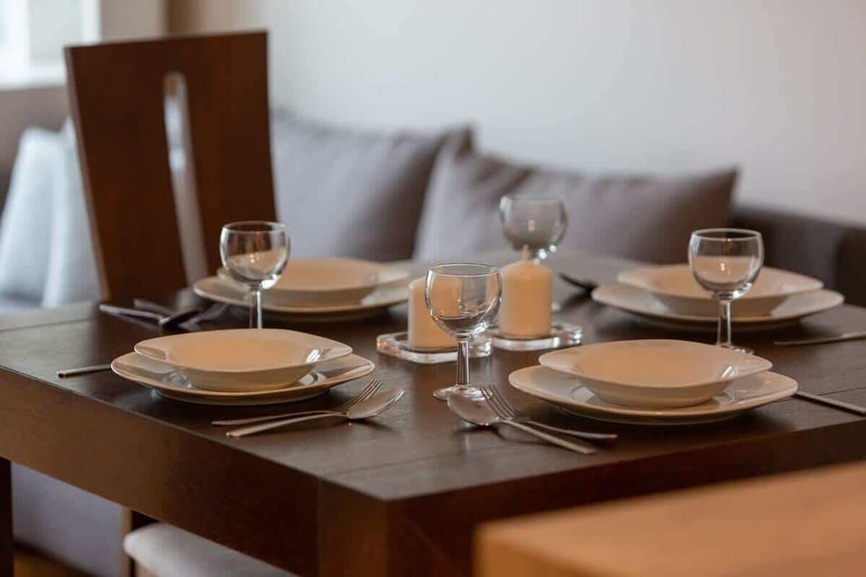 A close-up of a dining table set for four with plates, glasses, and a decorative centerpiece. The setting creates an inviting atmosphere for meals.