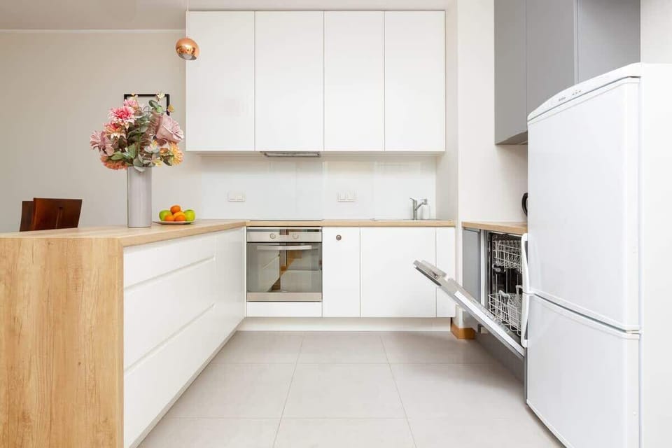 A closer view of a modern kitchen, showcasing sleek white cabinets, a compact countertop, and a clean, organized layout.
