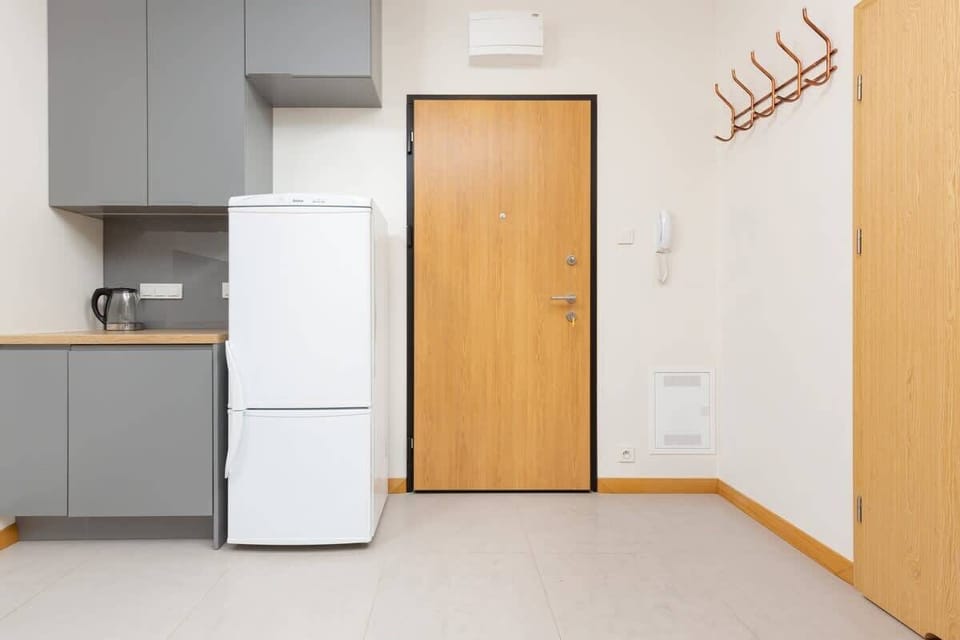 A compact kitchen corner with white cabinets, a small countertop, and essential appliances like a refrigerator and a stove.