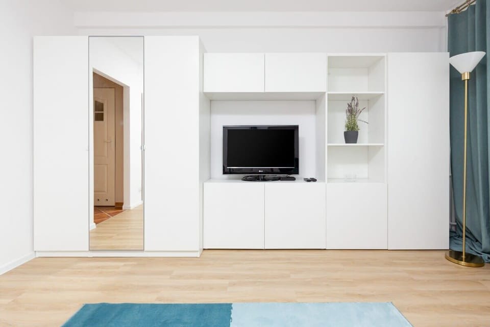A clean, modern living room showcasing a mounted flat-screen TV and white built-in storage cabinets.