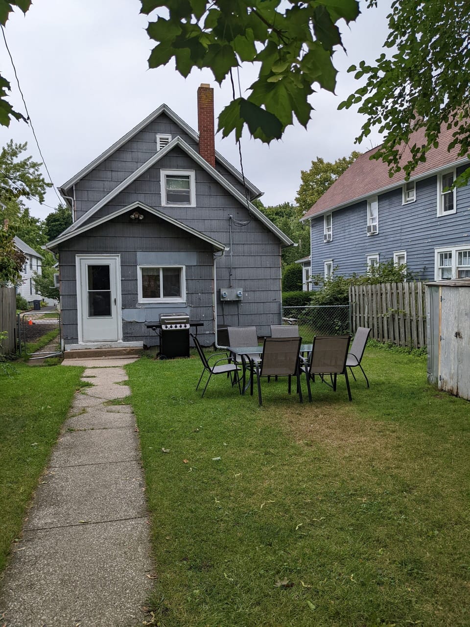 Backyard with gas grill and patio furniture. Door leads directly into lower unit