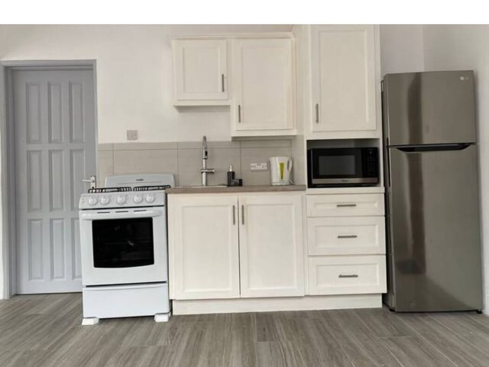 Full kitchen with microwave, gas stove and stainless steel fridge.