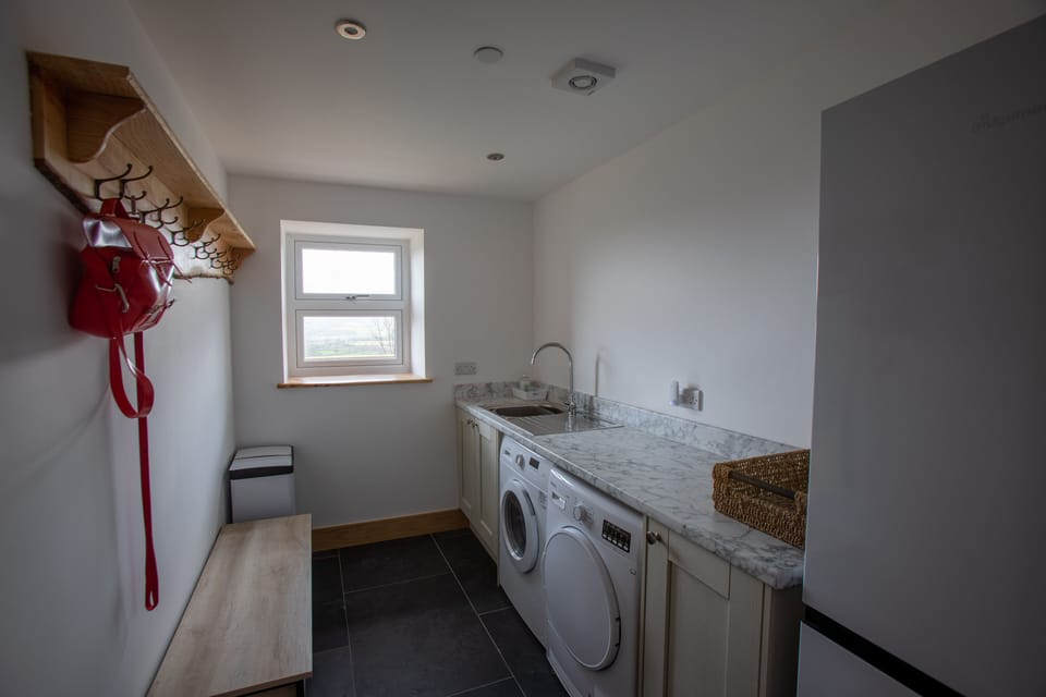 Utility room with washing machine, tumble dryer and fridge freezer