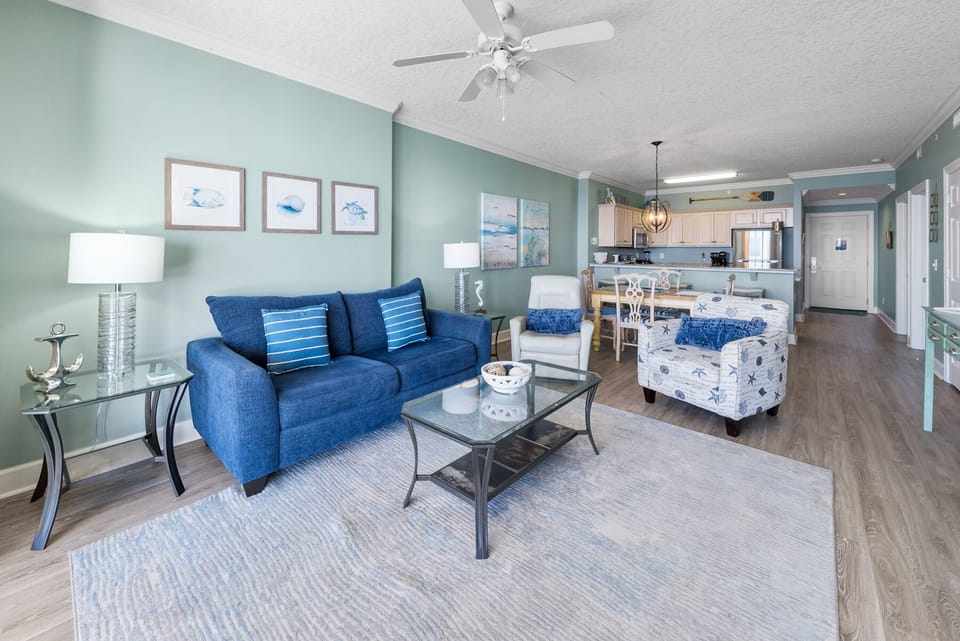 Relax in your coastal-themed living space with ocean blues and comfortable seating that flows seamlessly into your fully equipped kitchen.