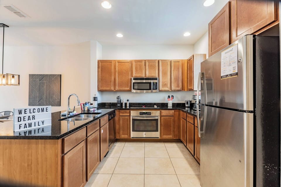 Discover a stunning kitchen with rich wooden cabinets and sleek black countertops, ideal for your culinary creations. Modern stainless steel appliances and warm lighting create an inviting atmosphere for family gatherings.