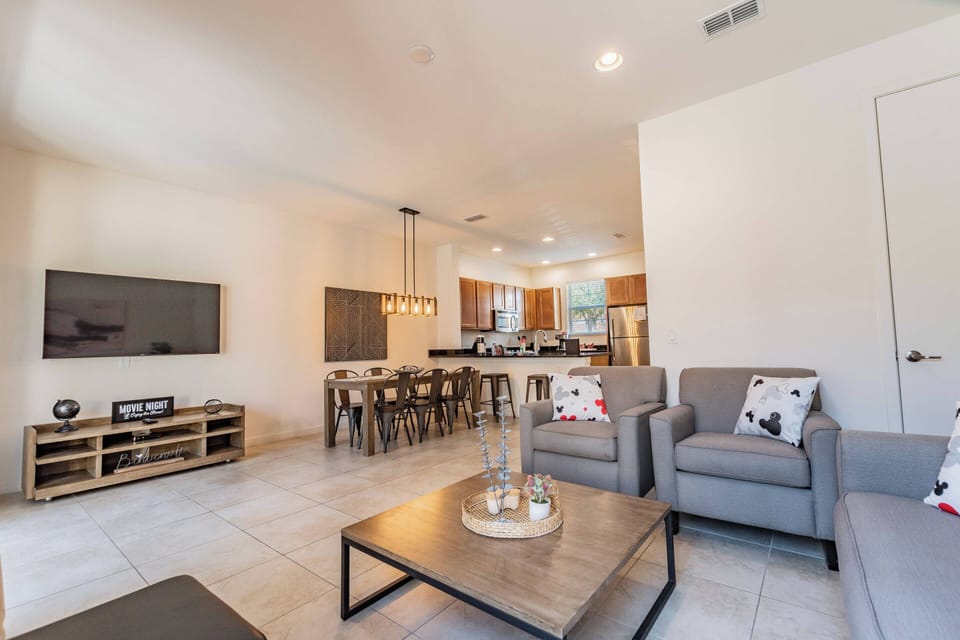 This spacious living area boasts sleek tile flooring and cozy seating, ideal for unwinding after your adventures. Natural light fills the space, showcasing modern decor and creating a warm, inviting atmosphere for relaxation.