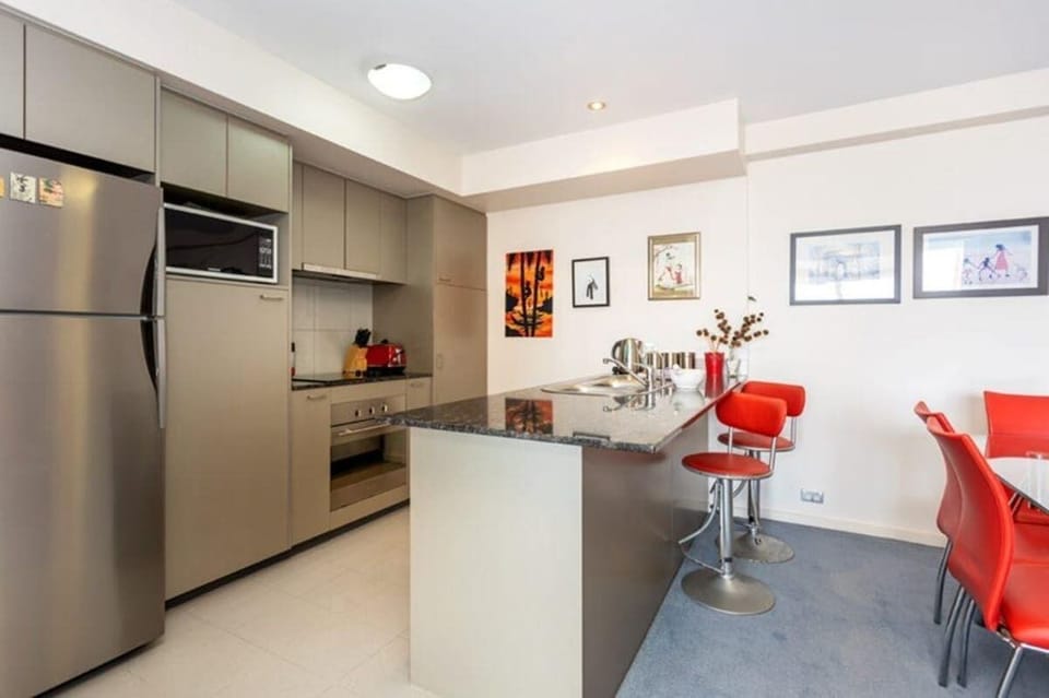 Enjoy cooking in this well-equipped kitchen featuring a convenient kitchen island, refrigerator, microwave oven, and stove. Ample kitchen cabinets provide plenty of storage, and comfortable chairs are available for seating.