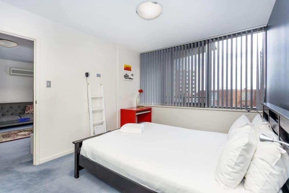 Enjoy a comfortable night's sleep in this inviting bedroom, complete with plush pillows, convenient tables, and windows that allow for natural light.