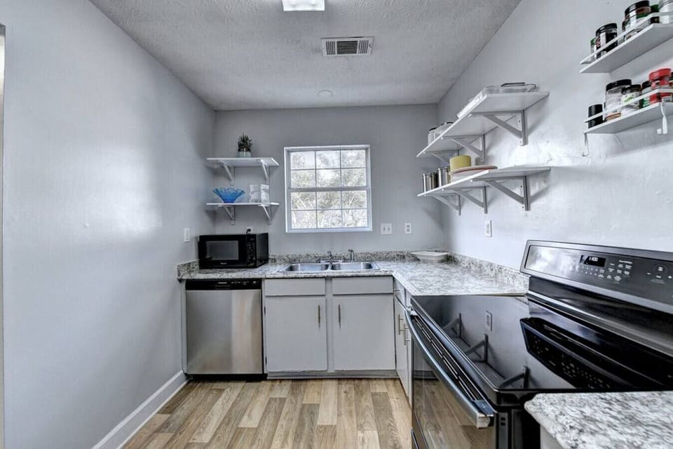 White kitchen: stove, microwave, sink, gas stove, window, drawers, clean design.