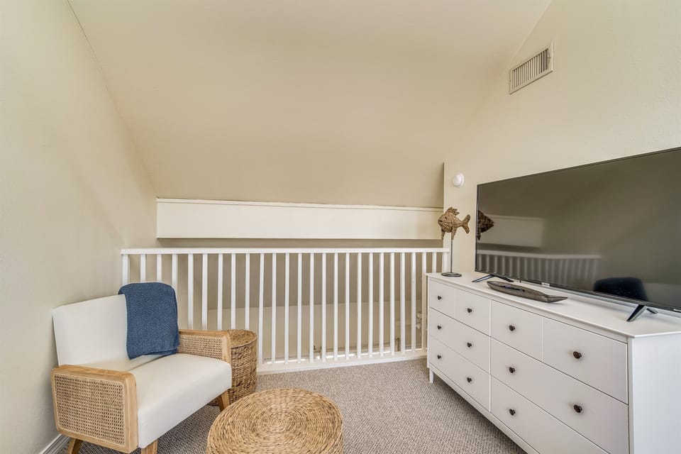 Upstairs loft with dresser storage and bedroom furnishings. Sand Dollar 206 East — renovated Pensacola Beach vacation condo on Little Sabine Bay.
