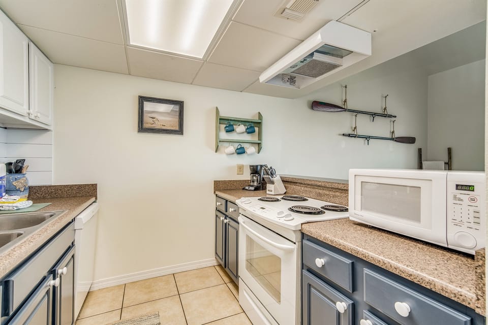 Kitchen with microwave, full appliance suite, and ample counter space for cooking. Renovated 1-bedroom loft vacation rental on Pensacola Beach, Florida.