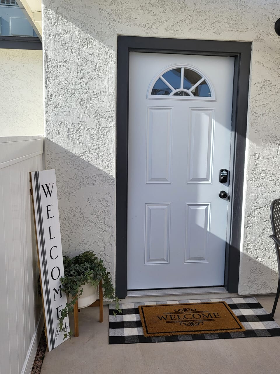 White front door entrance with a key and key pad for safe entry.  Covered porch