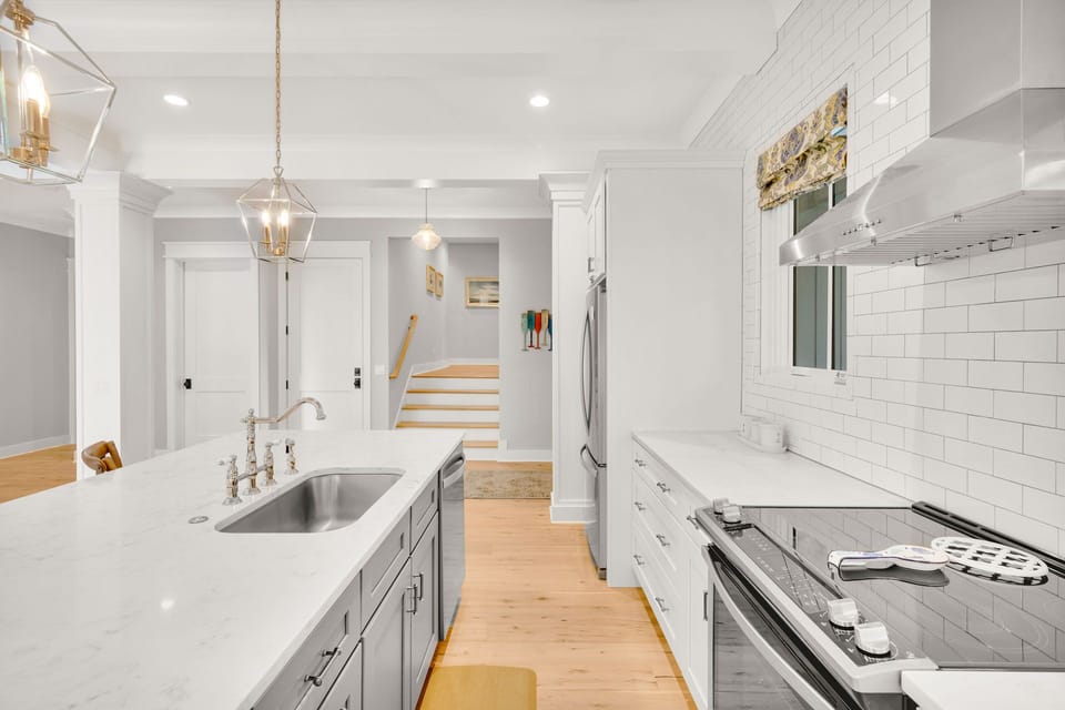 The kitchen offers ample counter space, stainless steel appliances, is fully stocked, and includes three barstools for additional seating.