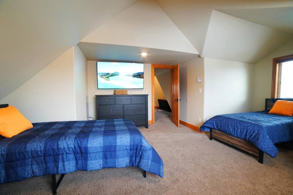 This upstairs bedroom has 2 twin beds, a sleeper sofa, and a large TV — a perfect getaway from the common area!