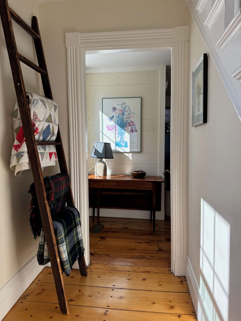 A cosy quilt and throws for cool evenings hang from an antique apple ladder.