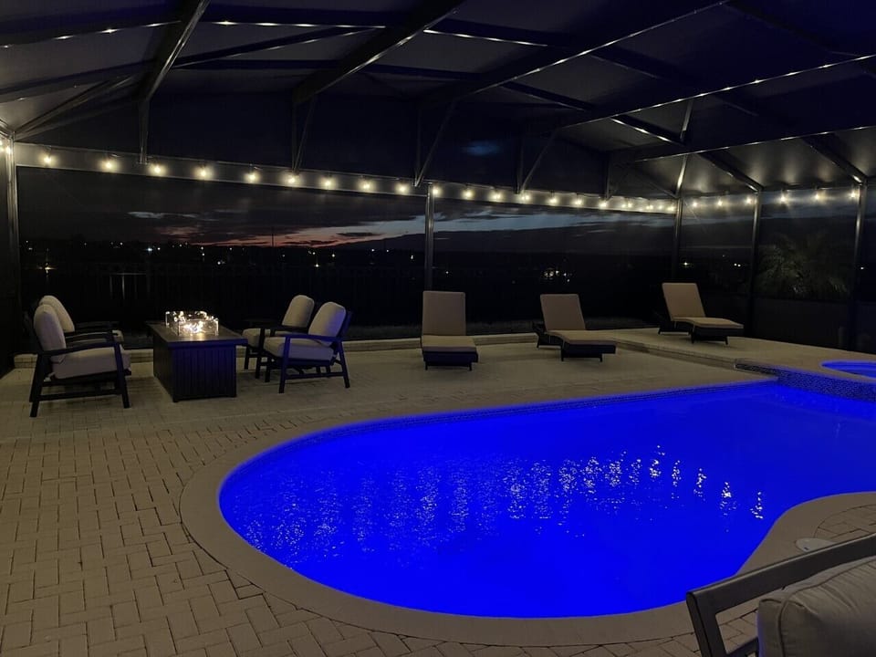 Resort style private pool featuring a fire table, luxury loungers and lights all around the pool!