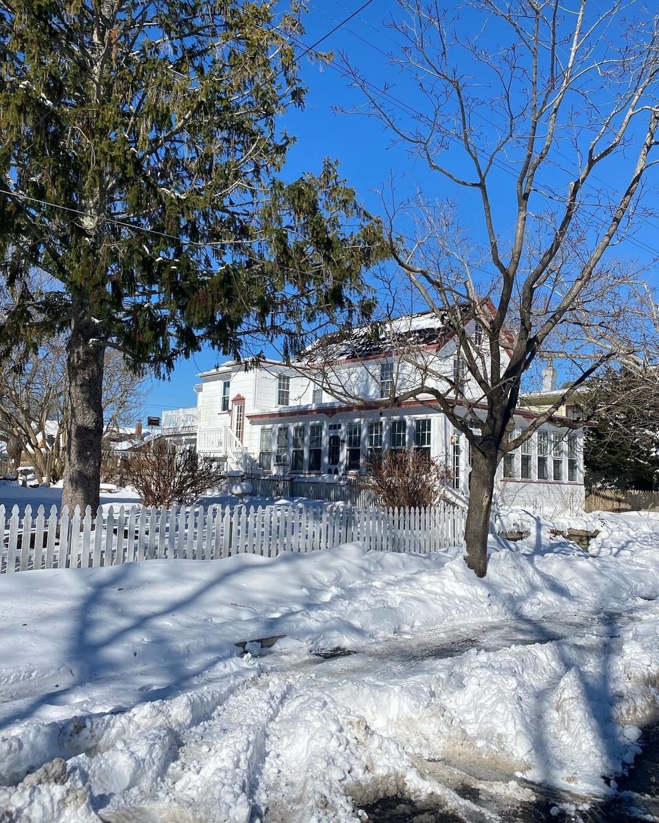 Side of house during a snow storm. Entrance for this unit is in the rear.