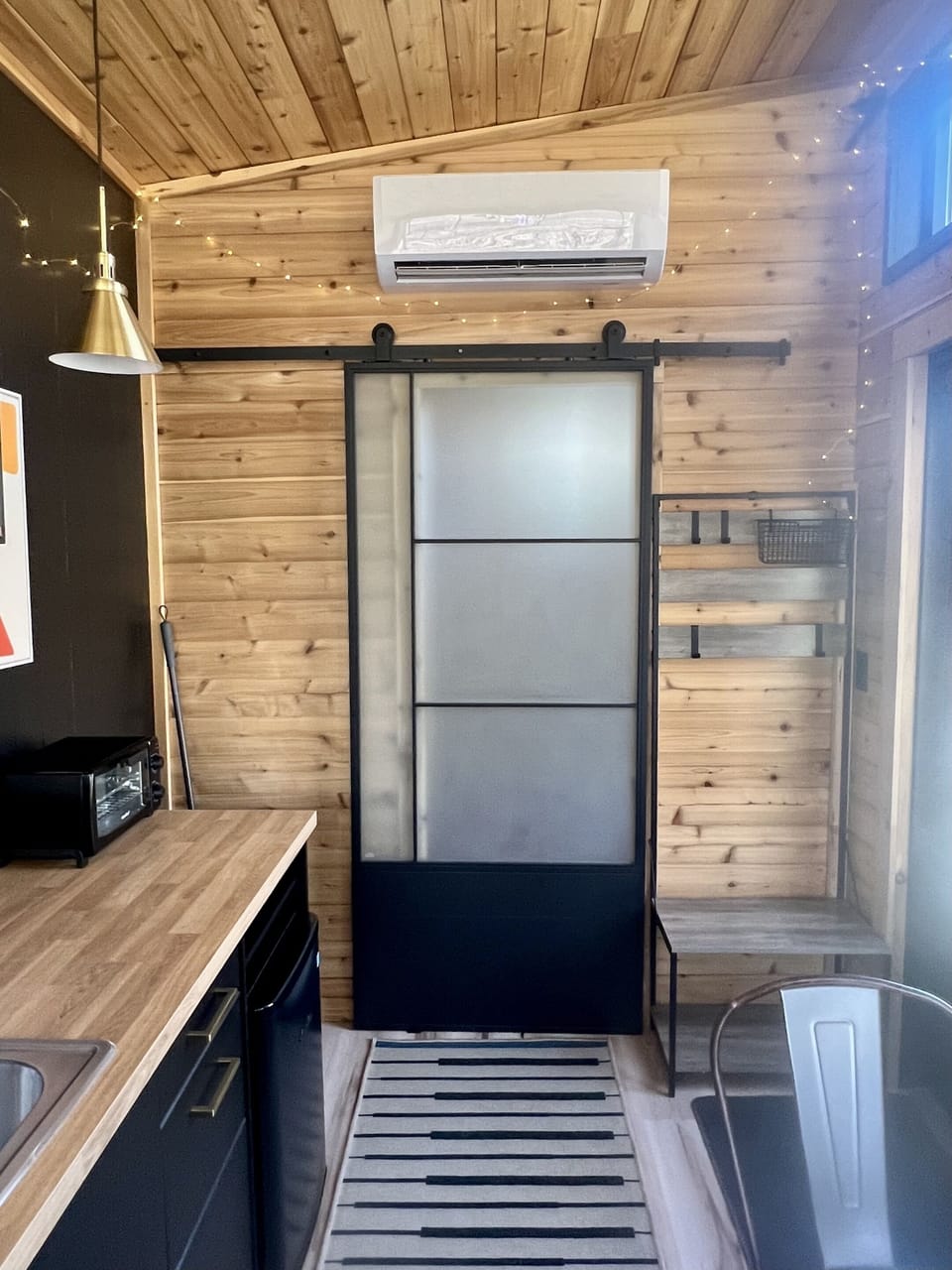This frosted sliding door separates the bathroom from the main room; the mini-split HVAC unit above the door keeps the entire space comfortable in all outdoor weather.  